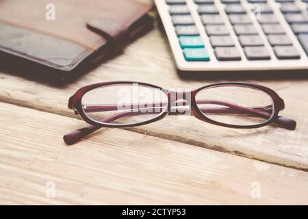 verres, calculatrice et portefeuille sur table en bois. Banque D'Images