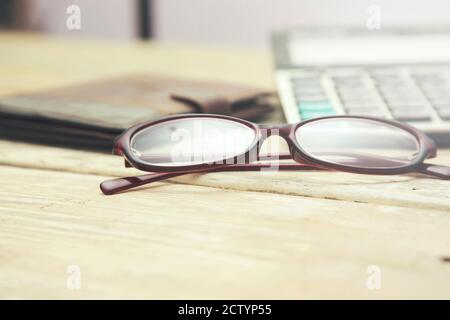 verres, calculatrice et portefeuille sur table en bois. Banque D'Images