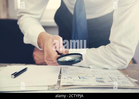 Businessman à travers une loupe aux documents Banque D'Images