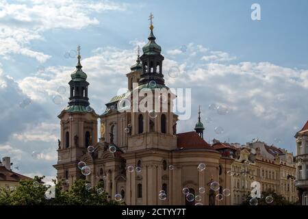 PRAGUE, RÉPUBLIQUE TCHÈQUE - 18 JUILLET 2019 : vue extérieure de l'église Saint-Nicolas avec bulles d'un artiste de rue Banque D'Images