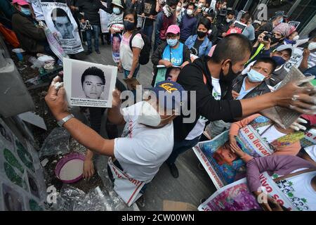 MEXICO, MEXIQUE - SEPTEMBRE 25 : une personne lève une photo d'un étudiant disparaît alors qu'une fresque commémore le 6e anniversaire des 43 élèves de l'école normale qui ont disparu le 26 septembre 2014. Les parents des 43 élèves d'Ayotzinapa lors d'une manifestation à l'extérieur du Procureur général de la République pour demander justice aux 43 élèves de l'Ecole normale rurale 'Raul Isidro Burgos' d'Ayotzinapanon 25 septembre 2020 à Mexico, Mexique. Crédit : Carlos Tischler/Eyepix Group/The photo Access Banque D'Images