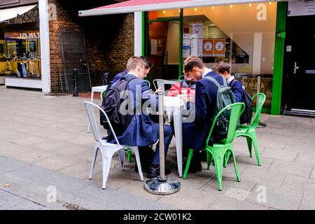 Groupe d'adolescents de Schoolboys repas à l'extérieur D'UN café à Uniforme scolaire Banque D'Images