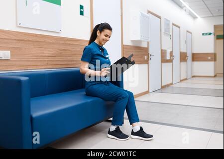 Femme chirurgien assise sur un canapé dans le hall de la clinique Banque D'Images