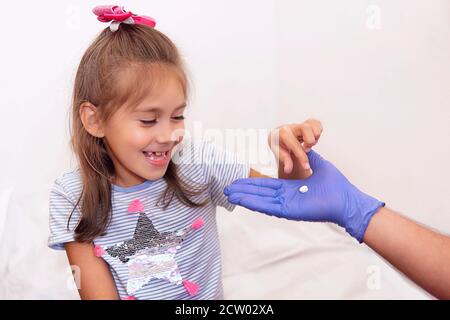 une jeune fille heureuse prend une pilule des mains d'un médecin à l'hôpital. Un patient qui récupère boit des vitamines. Traitement des rhumes et autres maladies Banque D'Images