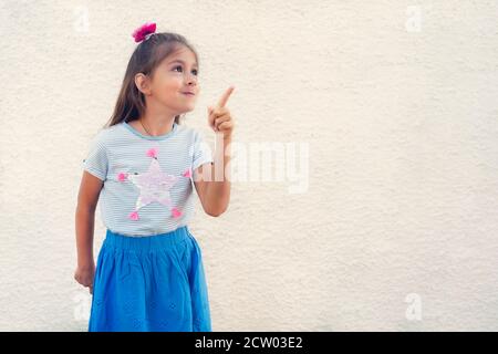 Jolie petite fille pointant vers le haut. Espace vide pour le texte et le design. Banque D'Images