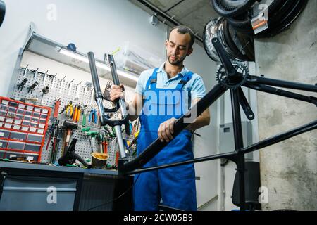 Montage de vélo en atelier, un homme installe la fourche Banque D'Images