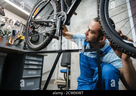 Réparation de vélo, un homme vérifie le jeu de la roue Banque D'Images