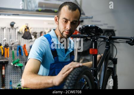 Réparation de vélo en atelier, un homme vérifie les pneus Banque D'Images