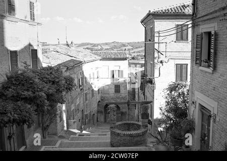 Un escalier dans un village médiéval italien avec un vieux puits en briques (Corinaldo, Marche, Italie, Europe) Banque D'Images