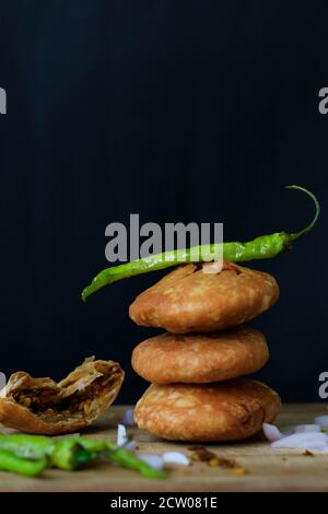 Délicieux en-cas indien kachori empilés les uns sur les autres et servis avec des piments verts et des oignons à fond noir. Banque D'Images