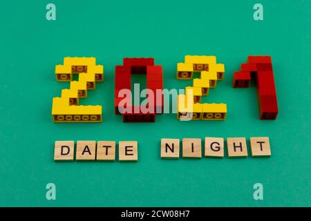 Les mots date Night 2021 sont tapissés de lettres en bois sur fond vert. Figures de la vue de dessus du constructeur. Carte postale en place pour le texte Banque D'Images