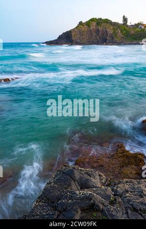 Des vagues blanches légèrement floues, avant l'aube, se roulent vers une côte rocheuse d'une Nouvelle-Galles du Sud, plage de la côte nord en Australie Banque D'Images