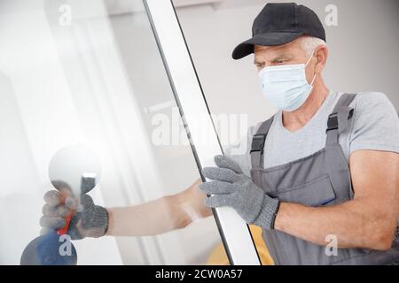 L'homme de travail dans le masque médical installe les fenêtres en plastique upvc et portes blanches avec ventouse de levage Banque D'Images