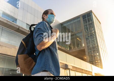 Vue en angle bas sur le handosme homme avec sac à dos et visage masque Banque D'Images
