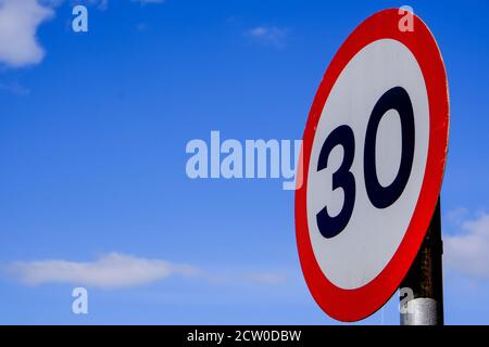 Signal de limite de vitesse de la circulation sur route à 30 mi/h, contre UN ciel bleu d'été Banque D'Images