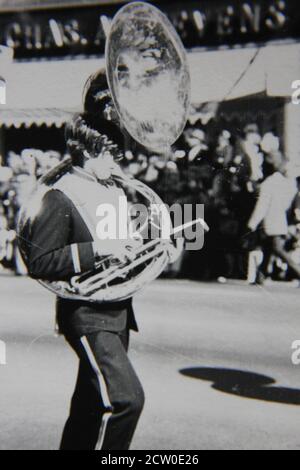 Belle photographie en noir et blanc vintage des années 1970 d'un joueur de tuba marchant dans un défilé du centre-ville. Banque D'Images