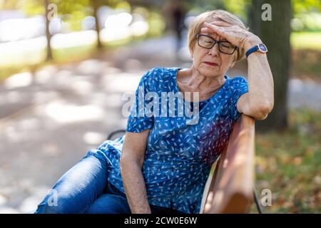 Femme âgée souffrant d'un mal de tête à l'extérieur dans la ville Banque D'Images