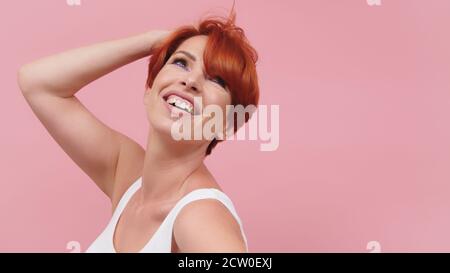 Âge moyen belle femme à tête rouge portant un sweat-shirt décontracté isolé sur fond rose avec un sourire heureux et frais sur le visage. Personne chanceux. Photo de haute qualité Banque D'Images