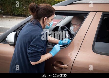 Un membre du public reçoit un vaccin contre la grippe assis dans sa voiture dans l'une des nouvelles cliniques de grippe du drive à Little France, Édimbourg. Banque D'Images