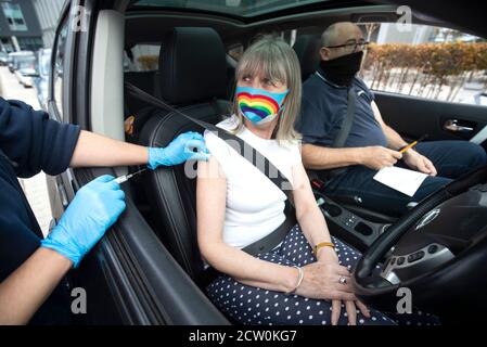 Un membre du public reçoit un vaccin contre la grippe assis dans sa voiture dans l'une des nouvelles cliniques de grippe du drive à Little France, Édimbourg. Banque D'Images