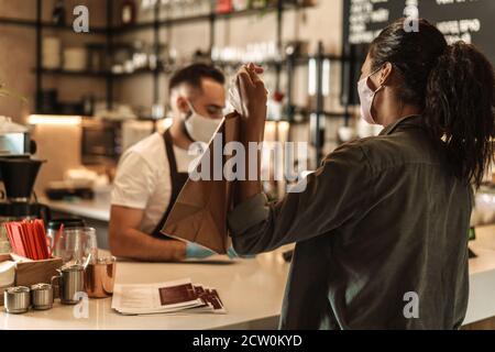 Client payant et prenant sa commande au café compteur pendant la quarantaine Banque D'Images