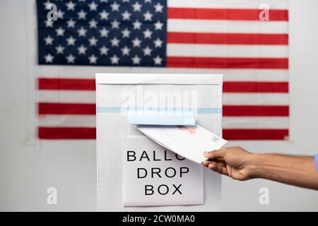 Maski, Inde 14 septembre, 2020 : concept de Mail en vote aux élections américaines - prise de vue grand angle des mains déposant le courrier à l'intérieur de l'urne avec notre drapeau Banque D'Images