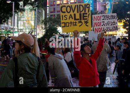 Une femme tenant un panneau de lecture, Covid-19 est un mensonge, tient un morceau de carton sur un haut-parleur pour protéger son bruit lors d'une petite manifestation ou "cluster festival" par des activistes japonais anti-masque à Hachiko Square, Shibuya, Tokyo, Japon. Samedi 26 septembre 2020.. Les militants sont partisans du controversé YouTuber devenu politicien plein d’espoir, Hiratsuka Masayuki, qui s’est présenté sans succès au gouverneur de Tokyo lors des élections du 5 juillet 2020 sous le parti libéral de souveraineté populaire. Banque D'Images