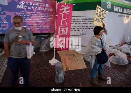 Covid est un mensonge, une femme tenant un panneau de lecture, tient un morceau de carton sur un haut-parleur pour protéger son bruit lors d'une petite manifestation ou d'un « festival de cluster » par des activistes japonais anti-masque à Hachiko Square, Shibuya, Tokyo, Japon. Samedi 26 septembre 2020.. Les militants sont partisans du controversé YouTuber devenu politicien plein d’espoir, Hiratsuka Masayuki, qui s’est présenté sans succès au gouverneur de Tokyo lors des élections du 5 juillet 2020 sous le parti libéral de souveraineté populaire. Banque D'Images