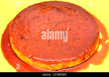 Gâteau à la crème caramel servi dans une assiette jaune désert Banque D'Images