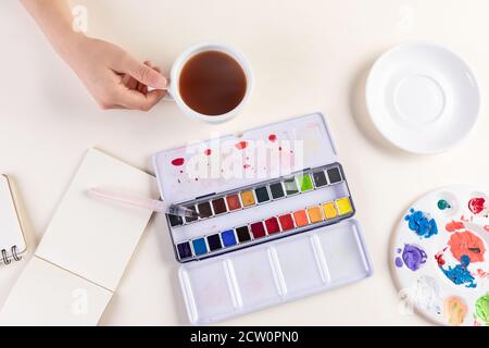 Gros plan d'un set aquarelle, d'un café et d'un bloc-notes Banque D'Images