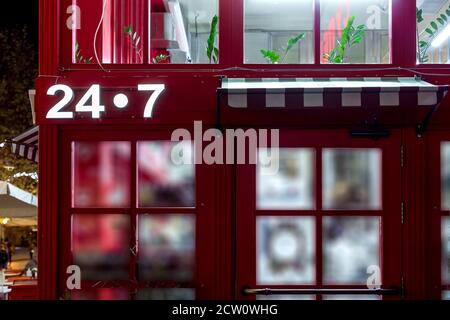 entrée au magasin rouge avec une voûte au-dessus de la porte avec un panneau lumineux 24/7 24 heures sur 24 dans le style anglais de l'architecture rouge, c Banque D'Images