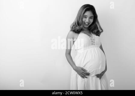 Portrait de jeune femme enceinte asiatique smiling against white background Banque D'Images