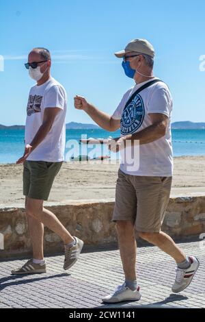Deux hommes masque de visage de waring marchent le long de la promenade à Los Alcazares à Murcie Espagne Banque D'Images