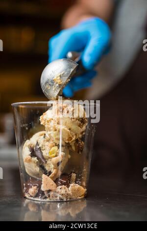 Préparation artisanale d'une tasse de verre de noix et de grains, glace italienne glace glace glace glace à la crème fouettée et biscuits à la langue du chat. Banque D'Images