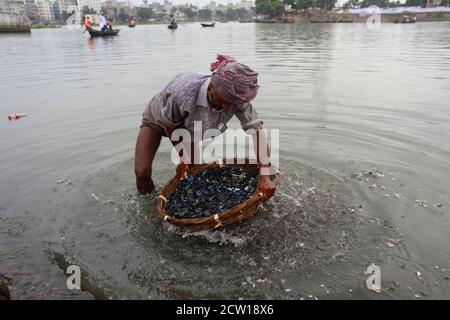 Dhaka, Bangladesh. 26 septembre 2020. Un homme bangladais lave les morceaux de matières plastiques usées dans la rivière Burigonga, Dhaka (Bangladesh), le 26 septembre 2020. Il y a environ 12-13 ans, le fleuve Buriganga était une voie d'eau populaire pour la communication et le transport de marchandises lorsqu'il coulait à travers Rasulpur à Kamrangirchar. Cependant, le Burigang ne peut plus être appelé une rivière car il a tellement rétréci qu'il est maintenant plus étroit qu'un canal. Les habitants de la région l'appellent maintenant une « rivière en plastique », même s'ils ont admis à la polluer avec des déchets en plastique. Dans la ville de Dhaka, plus de 14 millions de pièces de poly ba Banque D'Images