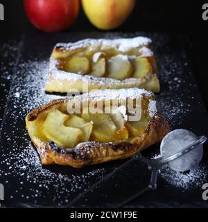 Tarte aux pommes phyllo arrosée de sucre glace sur fond sombre. Banque D'Images