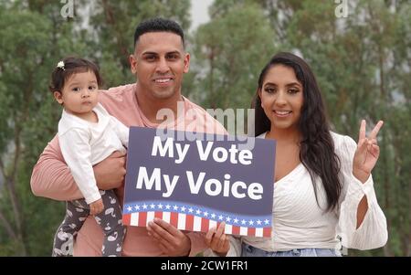 Une jeune famille Latino tient un signe de vote et sourit pour l'appareil photo Banque D'Images