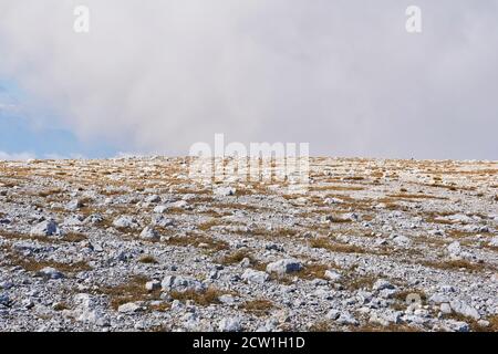 plateau alpin déserté recouvert d'herbe sèche et de pierres blanches Banque D'Images