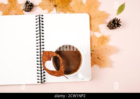 Composition d'automne. Plusieurs feuilles séchées, café lait latte tasse, pins cônes et carnet sur fond rose studio pour la publicité. Automne, automne Banque D'Images