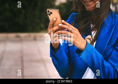 Bonne femme d'affaires souriante dans un blazer bleu avec smartphone. Envoyer des SMS, faire des achats en ligne ou consulter des réseaux sociaux Banque D'Images