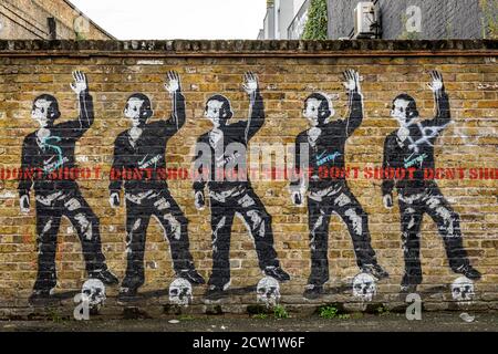 L'art Graffiti sur un mur dépeint des images qui s'opposent à la violence policière et au pouvoir des entreprises à Londres, au Royaume-Uni. Banque D'Images
