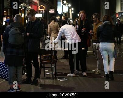 Un membre du personnel du bar qui se défaulait des tables et des verres vides à l'heure de fermeture à Soho, Londres, après que les pubs et les restaurants aient été soumis à un couvre-feu de 22:00 pour lutter contre l'augmentation des cas de coronavirus en Angleterre. Banque D'Images