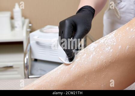 Une esthéticienne se prépare à cirer les jambes des femmes dans le centre de spa. Préparation pour l'épilation, en mettant un peu de poudre blanche Banque D'Images