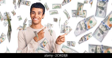 Jeune homme amérindien africain portant des vêtements décontractés souriant et regardant la caméra pointant avec deux mains et des doigts sur le côté. Banque D'Images