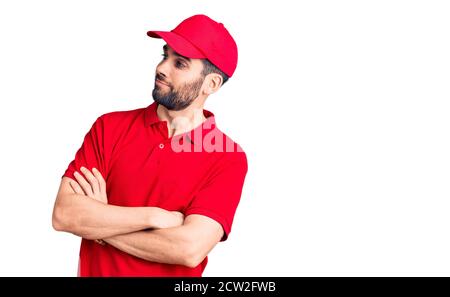 Jeune homme beau avec barbe portant l'uniforme de livraison regarder le côté aux bras croisés convaincu et confiant Banque D'Images