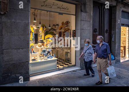 Barcelone, Espagne. 27 septembre 2020. Deux personnes portant des masques de visage comme mesure préventive devant une fenêtre de magasin avec des fans à Plaza de Sant Jaume.Barcelona continue sous la pandémie Covid avec des niveaux élevés de repousse et avec l'utilisation obligatoire d'un masque sanitaire dans les espaces publics. Crédit : SOPA Images Limited/Alamy Live News Banque D'Images