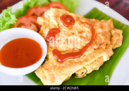 Omelette avec tomates en tranches salade laitue légumes sur assiette blanche / oeufs omelette petit déjeuner et sauce tomate sur le dessus Banque D'Images