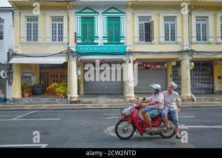 Un couple en moto passe devant les boutiques chinoises-portugaises colorées de Thalang Rd. Dans la vieille ville (Chinatown) de Phuket Town, en Thaïlande Banque D'Images