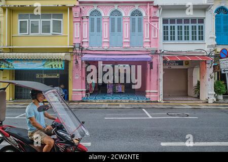 Un homme sur une moto couverte de toit passe devant les boutiques chinoises-portugaises colorées de Thalang Road, dans la vieille ville de Phuket, en Thaïlande Banque D'Images