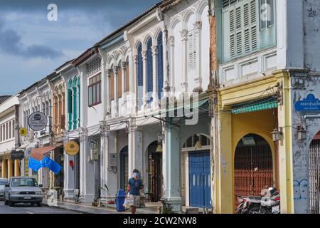 Un homme marche le long d'une rangée de boutiques chinoises-portugaises colorées dans la rue Yaowarat dans la vieille ville (Chinatown) de Phuket Town, Thaïlande Banque D'Images